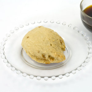 Butter brickle scone made with butter brickle scone mix sitting on a clear glass plate. There is a cut of coffee just off to the side of the plate.