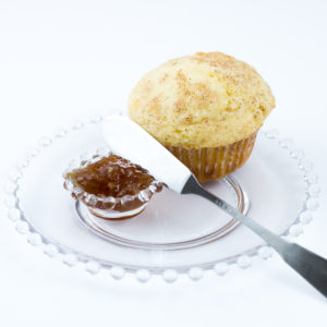 Muffin baked with Classic Homestyle Muffin Mix sitting on clear glass plate with spreading knife and dish of jam