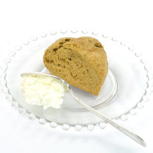 Gingerbread Scone made with Gingerbread Scone Mix. The scone is sitting on a clear glass plate; the plate also has a dollop of Devonshire cream and a knife--just ready for someone to split the scone and spread this on the scone prior to eating.