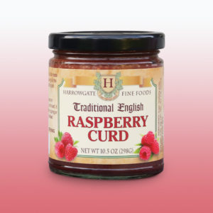 A jar of Raspberry Curd made by Harrowgate Fine Foods. Clear glass jar; black lid, picture of raspberries on the label.