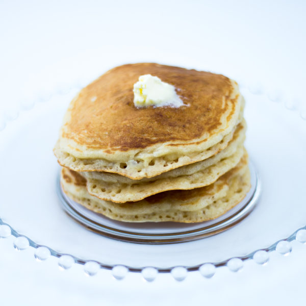 Short stack of atmeal pancakes made with oatmeal pancake mix with pat of butter on top, on glass plate.