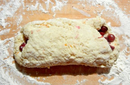 Scone dough with flecks of orange zest in dough folded around fresh cranberries